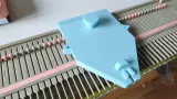 Light blue unraveling carriage on a Silver Reed LK150 knitting machine