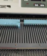 Assembly stop ruler pushing needles on a Brother knitting machine bed