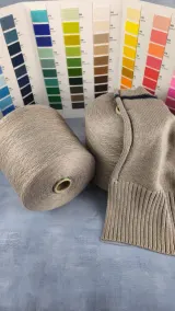 Grey beige melange cotton acrylic yarn cone with a knitted sweater and colour card