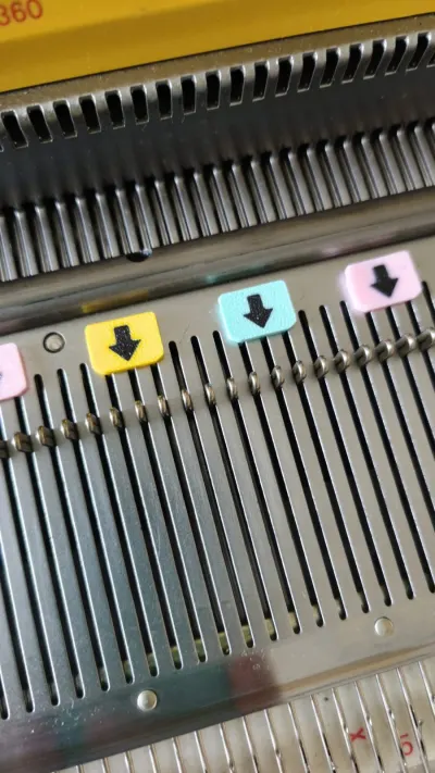 Pastel 3D-printed needle bed markers on a Silver Reed knitting machine main bed