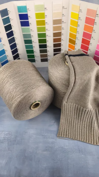 Grey beige melange cotton acrylic yarn cone with a knitted sweater and colour card