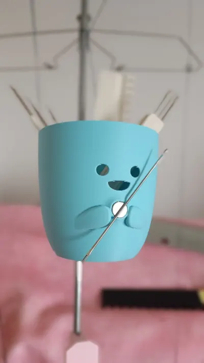 Cute blue cat-face tool organizer on the yarn tension mast holding knitting machine tools
